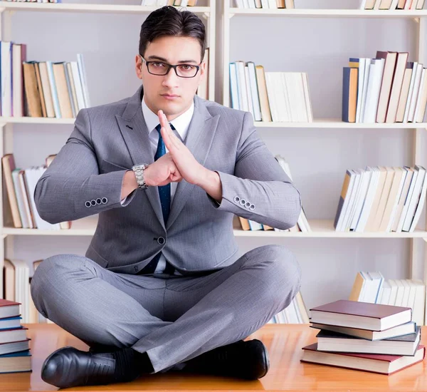 Студент бізнесмена в позиції лотоса, що концентрується в бібліотеці — стокове фото