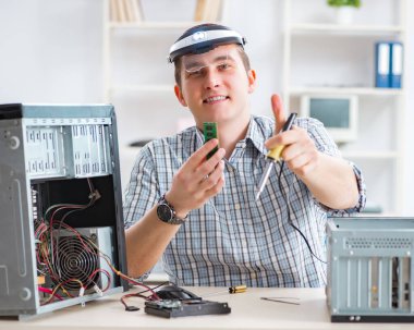 Genç teknisyen atölyede bilgisayar tamir ediyor.