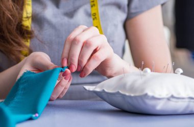 Kadın terzi dikiş dikmek için dikiş dikiyor.