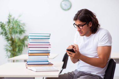 Sınıfta oturan genç erkek öğrenci.