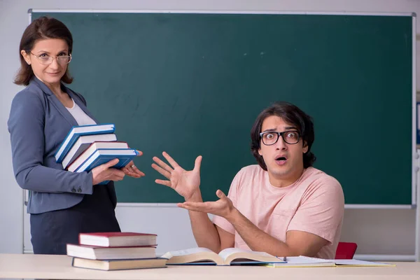 Gammal kvinnlig lärare och manlig student i klassrummet — Stockfoto