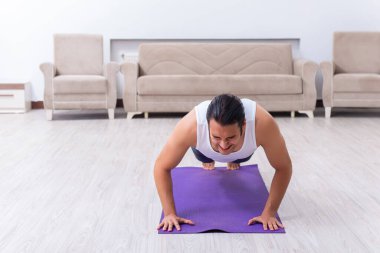 Genç adam evde antrenman ve egzersiz yapıyor.