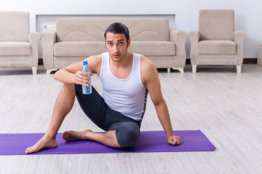 Genç adam evde antrenman ve egzersiz yapıyor.