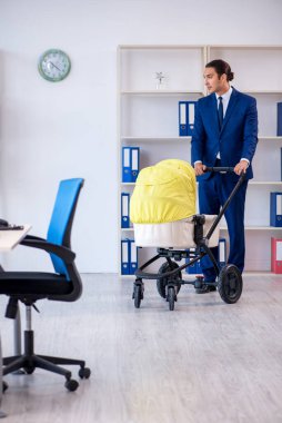 Genç baba ofiste yeni doğan bebeğe bakıyor.