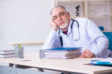Klinikte çalışan yaşlı erkek doktor.