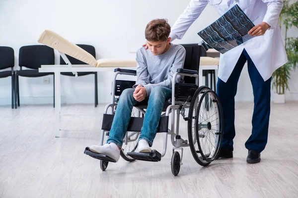 Joven doctor pediatra y niño en silla de ruedas —  Fotos de Stock