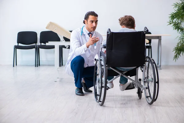 Genç erkek doktor pediatrist ve tekerlekli sandalyedeki çocuk. — Stok fotoğraf