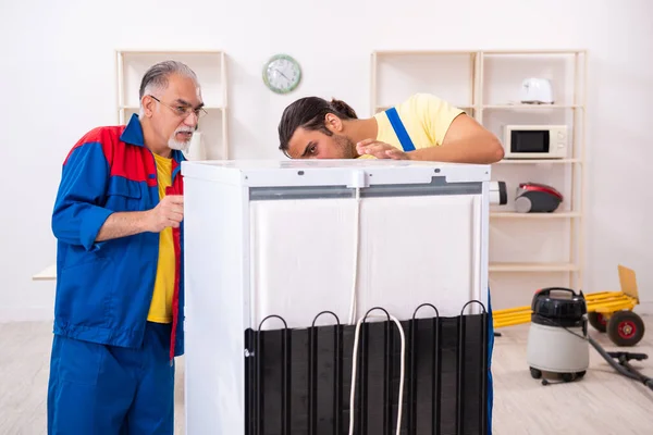 Dos contratistas reparan refrigerador en taller — Foto de Stock