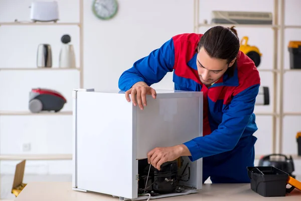 Joven contratista reparando refrigerador en taller — Foto de Stock
