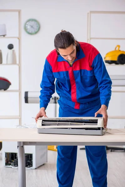 Jonge mannelijke aannemer repareert airconditioner in werkplaats — Stockfoto