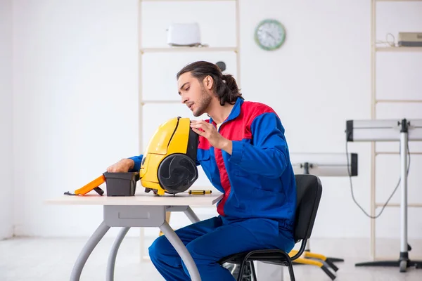 Young male contractor repairing vacuum cleaner at workshop — Stock Photo, Image