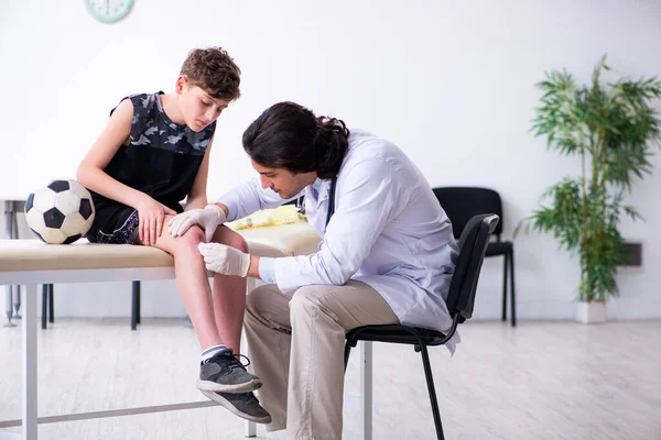 Niño jugador de fútbol visitando joven médico traumatólogo — Foto de Stock