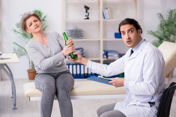 Mujer alcohólica visitando joven doctor masculino — Foto de Stock