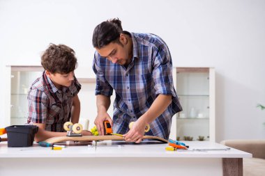 Genç baba oğluyla kaykay tamir ediyor.