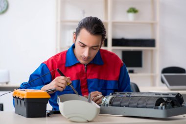 Garanti merkezinde klima tamiri yapan genç bir tamirci.