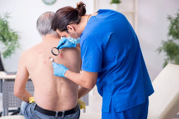 Starý muž návštěva mladý lékař dermatolog — Stock fotografie