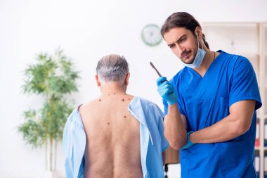 Yaşlı adam genç erkek doktor dermatoloğu ziyaret ediyor.