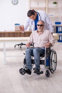 Yaşlı kör adam genç erkek doktoru ziyaret ediyor.