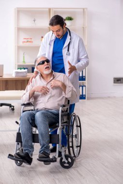 Yaşlı kör adam genç erkek doktoru ziyaret ediyor.