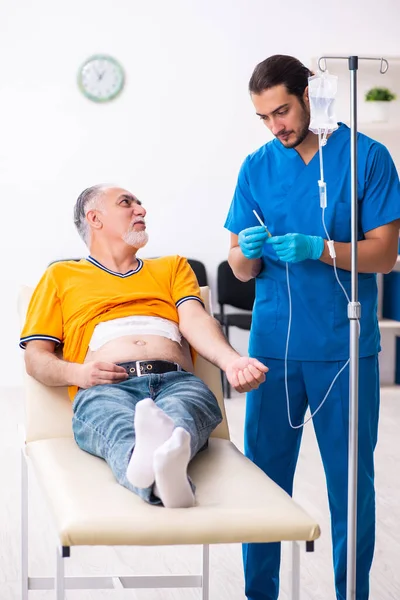 Viejo visitando joven doctor masculino —  Fotos de Stock