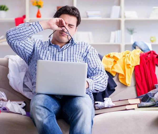 Jeune homme travaillant dans une chambre désordonnée — Photo