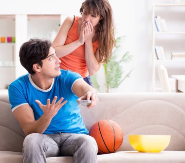 Adam karısıyla basketbol seyrediyor.