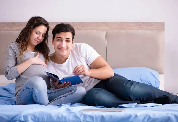 Mladá rodina s těhotnou ženou očekává dítě v posteli — Stock fotografie