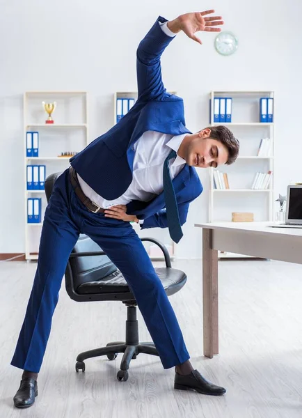 Giovane uomo d'affari che fa sport stretching sul posto di lavoro — Foto Stock