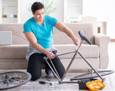 Evde bisiklet tamir eden genç bir adam.