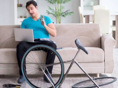 Evde bisiklet tamir eden genç bir adam.