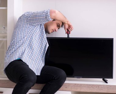 Evdeki bozuk televizyonu tamir eden adam.