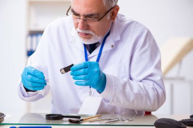 Kanıt için laboratuvarda çalışan yaşlı bir erkek kriminolog.