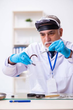 Kanıt için laboratuvarda çalışan yaşlı bir erkek kriminolog.