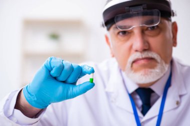 Kanıt için laboratuvarda çalışan yaşlı bir erkek kriminolog.