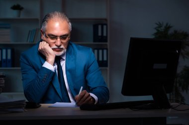 Eski erkek çalışan ofiste geç saatlere kadar çalışıyor.