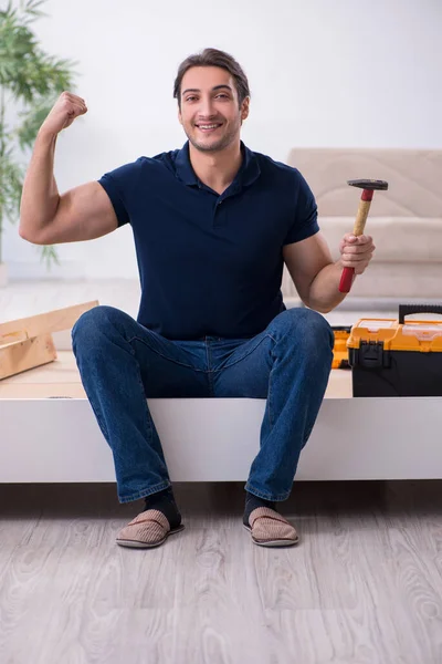 Jovem empreiteiro masculino instalando móveis em casa — Fotografia de Stock