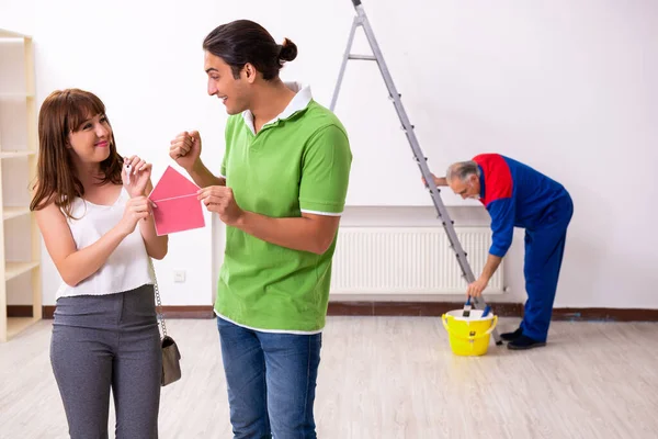 Young couple and old contractor in home renovation concept — Stock Photo, Image
