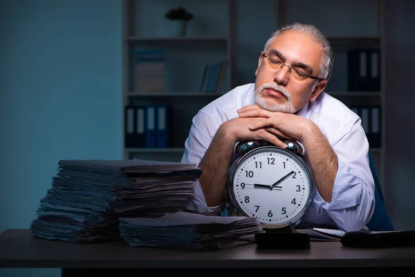 Oude mannelijke werknemer die laat op kantoor werkt — Stockfoto