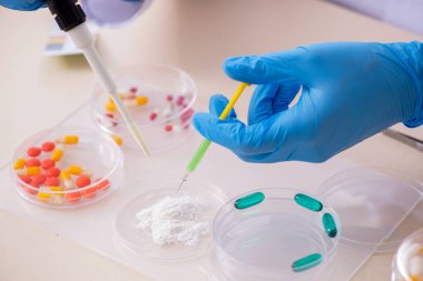 Uyuşturucu sentezi konseptinde genç erkek laboratuvar asistanı