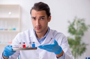 Uyuşturucu sentezi konseptinde genç erkek laboratuvar asistanı