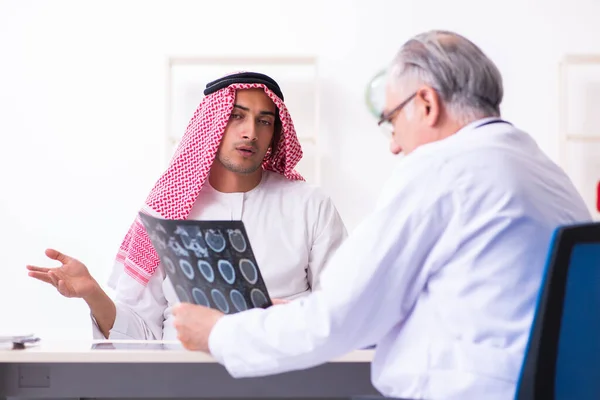 Young male arab visiting experienced male doctor — Stock fotografie