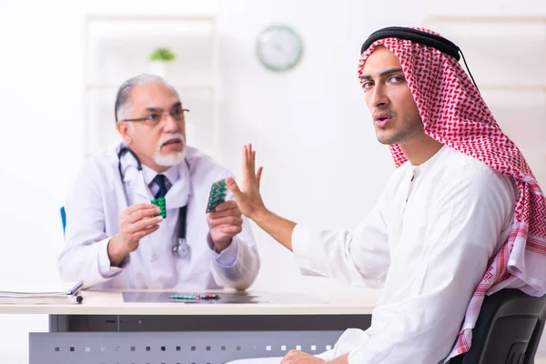 Young male arab visiting experienced male doctor — Stock fotografie