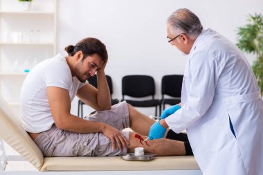 Yaralı adam ilk yardım konseptinde yaşlı doktoru ziyaret ediyor.