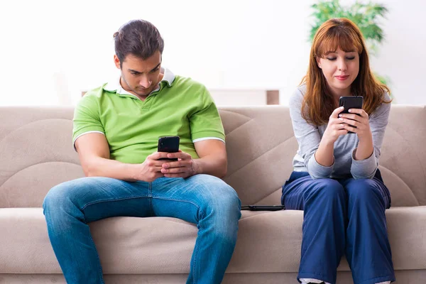 Pareja joven en concepto de dependencia gadget — Foto de Stock