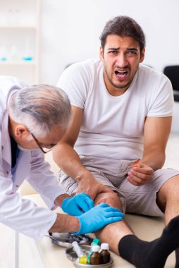 Yaralı adam ilk yardım konseptinde yaşlı doktoru ziyaret ediyor.