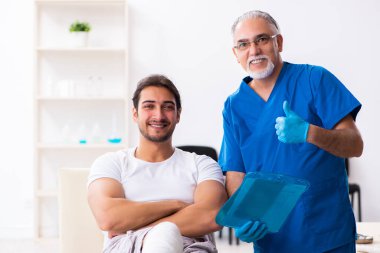 Yaralı adam ilk yardım konseptinde yaşlı doktoru ziyaret ediyor.