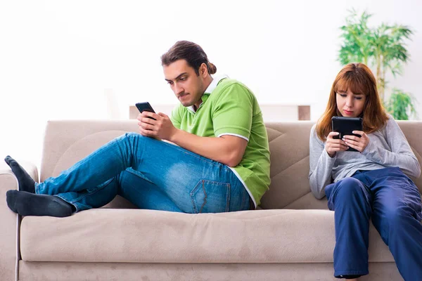 Pareja joven en concepto de dependencia gadget — Foto de Stock