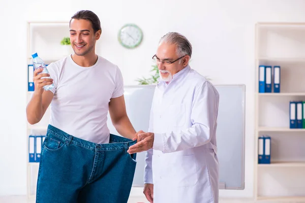 Medico dietista e paziente felice indossa pantaloni di grandi dimensioni — Foto Stock