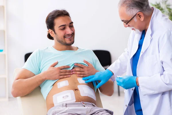 Ferito giovane uomo in visita esperto medico maschio — Foto Stock