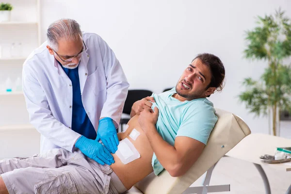 Ferito giovane uomo in visita esperto medico maschio — Foto Stock